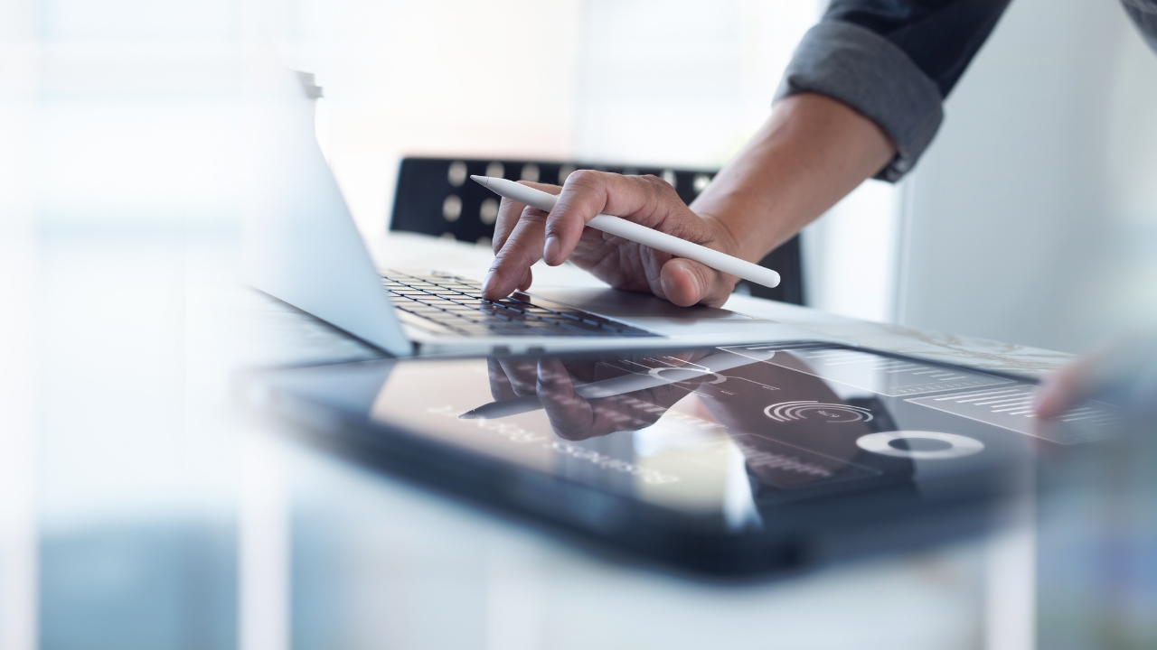 Osoba radi na laptopu uz tablet i analitiku na ekranu, što jasno prikazuje digitalni marketing u praksi